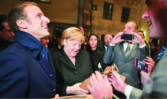 ?? REUTERS ?? Los viandantes obsequian a Emmanuel Macron y a Angela Merkel con botellas de vino antes de la cena celebrada en el castillo de Clos de Vougeot