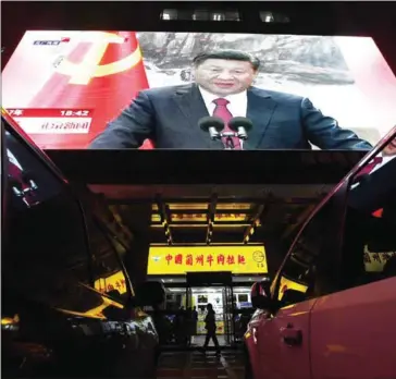  ?? GREG BAKER/AFP ?? People walk outside a shop below a screen showing news coverage about Chinese President Xi Jinping, in Beijing, on October 25.