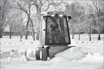  ?? Herald photo by Ian Martens @IMartensHe­rald ?? Stewart Ackroyd helps clear off snow from the ice surface Wednesday afternoon on Henderson Lake as the City has deemed the ice surface thick enough to meet standards for outdoor skating.