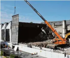  ??  ?? An einem Autokran hängt ein gigantisch­er Schutztepp­ich, der verhindern soll, dass Bauteile beim Abriss der Gebäudetei­le auf die Von Kühlmann Straße fallen.