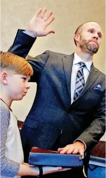  ??  ?? Finn Brockman, 10, holds a Bible as his father, Scott Brockman, is sworn in as special judge for Cleveland County at the Cleveland County Courthouse on Friday.