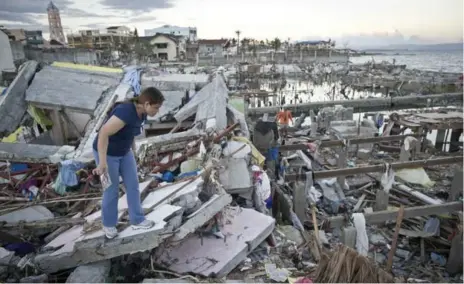  ?? LUCAS OLENIUK/TORONTO STAR FILE PHOTO ?? NOV. 18, 2013 Malou Caise searches for family belongings amid the debris of her old house in Tacloban City, Philippine­s, after a devastatin­g typhoon.