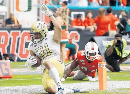  ?? WILFREDO LEE/AP ?? Georgia Tech running back Nathan Cottrell scores a touchdown against Hurricanes defensive lineman Josh Neely during Saturday’s game.