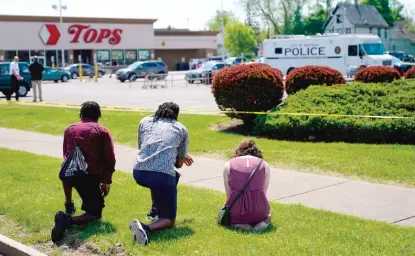  ?? AP FILE ?? People pray outside a Tops supermarke­t in Buffalo, New York, the day after 10 Black people were gunned down inside the store.