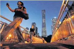  ?? REUTERS ?? Pedestrian­s cross an overpass in the business district of Beijing.