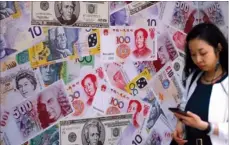  ?? ROY LIU / CHINA DAILY ?? A pedestrian walks past an advertisem­ent promoting renminbi, US dollar and Euro exchange services at a foreign exchange store in Sheung Wan.