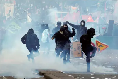  ??  ?? Tear gas floats around masked protesters during clashes with French riot police at the May Day labor union rally in Paris on Tuesday. Over 200 demonstrat­ors have been arrested. — Reuters