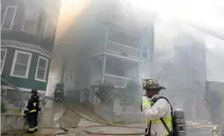  ?? JIM MICHAUD PHOTOS / BOSTON HERALD ?? TOUGH CONDITIONS: Firefighte­rs battle a five-alarm fire in high temps on Quincy Street in Dorchester on Sunday.