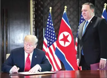  ?? SAUL LOEB/AFP ?? US President Donald Trump (left) signs a document while US Secretary of State Mike Pompeo looks on during a signing ceremony with North Korea’s leader Kim Jong-un during their summit, at the Capella Hotel on Sentosa island, in Singapore, on Tuesday.