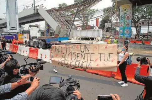  ?? AFP ?? Dos mujeres protestan en el lugar donde el lunes se desplomó un tramo de un puente elevado del metro