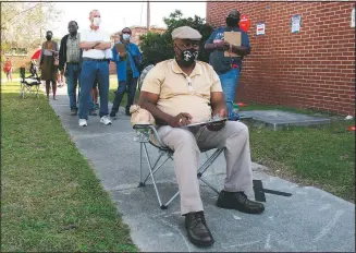  ?? (AP/Russ Bynum) ?? Richard Williams sits in a folding chair, filling out paperwork, as he waits in line to vote early Wednesday in Savannah, Ga.