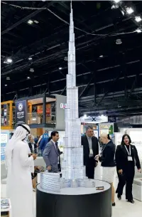  ??  ?? Visitors at the Dubai pavilion show interest in a model of the Burj Khalifa.