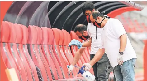  ?? FOTO: MATTHIAS HANGST/DPA ?? Das DFL-Hygienekon­zept beinhaltet viele Facetten. Hier desinfizie­ren Helfer die Ersatzbänk­e im Nürnberger Stadion.