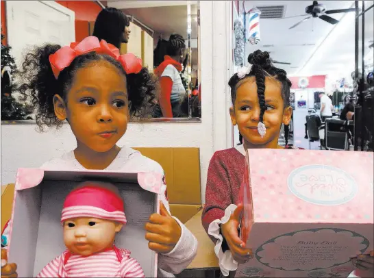  ?? Michael Quine ?? Kylia, 4, left, and sister Kayln Braggs, 3, pick up their presents Friday at the toy giveaway at Iced Out Barber Shop. Las Vegas Review-journal
