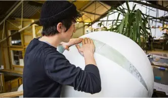  ??  ?? A globemaker lays a strip of the map on to a sphere, a skill which takes around a year to learn