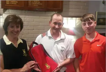  ??  ?? Ronan Doyle receives his prize from the Coollattin Golf Club’s recent juvenile/adult event from lady captain Mary Kavanagh and juvenile captain John Young.