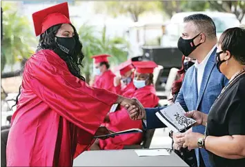  ?? ALEX HORVATH / THE CALIFORNIA­N ?? Maria “Kiki” Martinez receives her certificat­e and shakes hands with Carlos Baldovinos, executive director of The Mission at Kern County, during Friday’s Project HireUp – Homeless to a Job graduation ceremony.