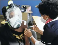  ??  ?? A doubly masked Capetonian receives the Covid-19 vaccine at the Hope Exchange. While the national health department thinks about how to register undocument­ed people for the vaccine, the Western Cape is rolling out jabs.