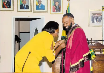  ?? CONTRIBUTE­D ?? Tracy Reynolds (left) director of Administra­tion at the St. Elizabeth Municipal Corporatio­n, adjusting the robe of the corporatio­n’s newly installed mayor, Councillor Richard Solomon.