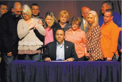  ?? Robert Ray ?? The Associated Press The parents of deceased 15-year-old Bailey Holt, left, stand in tears as Kentucky Gov. Matt Bevin signs a prayer proclamati­on Friday in Benton, Ky. Marshall County High School reopened its doors after two students were killed at...