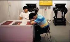  ?? ALEXANDER F. YUAN ASSOCIATED PRESS ?? Bored furniture traders wait for customers during a consumer products exhibition Friday in China’s capital, Beijing.