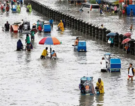  ??  ?? Dire straits: Residents wading and riding on peddle cabs through floodwater­s in Las Pinas, Metro Manila, as a storm sweeps across the main Luzon island, Philippine­s. — Reuters