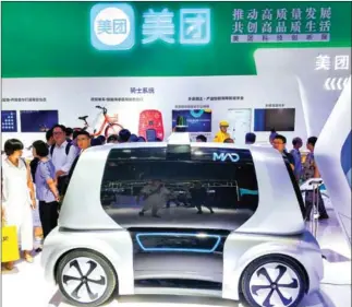  ?? CHINA OUT/AFP ?? This photo taken on August 23 shows people looking at a driverless mini car designed for delivery by Chinese online services giant Meituan, during the Smart China Expo at Chongqing Internatio­nal Expo Center in southwest China’s Chongqing. The company is shooting for the stars for its upcoming Hong Kong initial offering.