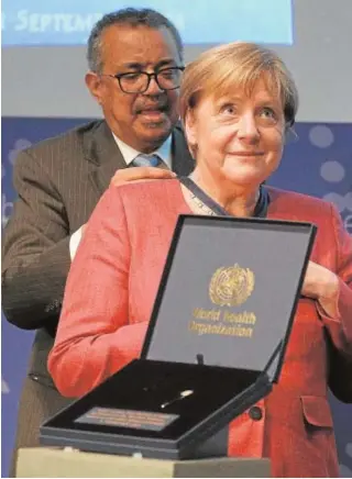 ?? // EFE ?? El director general de la OMS distingue el trabajo de Angela Merkel, ayer
