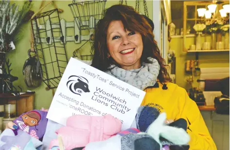  ?? [FAISAL ALI / THE OBSERVER] ?? Woolwich Lions Club member Freda Walker with a box full of warm clothing at The Windox Box store in downtown Elmira. The Lions will be accepting donations for their Toasty Toes campaign until Nov. 26, with all the clothing going to benefit oneRoof in Waterloo Region.