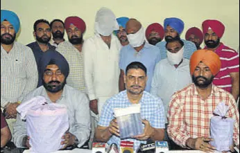  ?? SAMEER SEHGALHT ?? Special task force officials with the heroin seized from three accused (standing with faces covered) in Amritsar on Saturday.