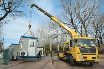  ?? JADE GAO/GETTY-AFP ?? Chinese workers haul away a COVID-19 testing booth Feb. 8 at a park in Beijing.