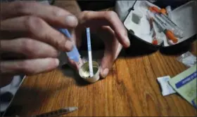  ?? BEBETO MATTHEWS — THE ASSOCIATED PRESS ?? An addict prepares heroin, placing a fentanyl test strip into the mixing container to check for contaminat­ion, Wednesday in New York. If the strip registers a “pinkish” to red marker then the heroin is positive for contaminan­ts.