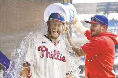  ?? DERIK HAMILTON/AP ?? Philadelph­ia Phillies starting pitcher Zack Wheeler is doused with water in the dugout by teammate Zack Eflin after a victory against the New York Mets on Aug. 8 in Philadelph­ia. Wheeler and Ranger Suarez are expected to pitch well but there are questions about the other starters.