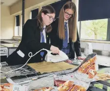  ?? ?? Marcie Sloan, 13, and Katie Belford, 12, iron the packets together.