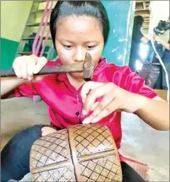  ?? SUPPLIED ?? A young woman working at Madam Chnai’s copper workshop.