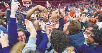  ?? ADRIAN KRAUS / ASSOCIATED PRESS ?? Syracuse guard Quadir Copeland, middle, celebrates with fans who rushed the court after the team’s Feb. 13 win over North Carolina in Syracuse, N.Y.