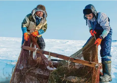  ?? Fotos: Philipp Hannappel ?? Das kleine Volk der Niwchen auf der russischen Insel Sachalin lebt vom Fischfang: Ruslan Njawan (links) und sein Bruder Michail ziehen ihr Netz aus dem zugefroren­en Meer. Bei minus 45 Grad ist das Schwerstar­beit.