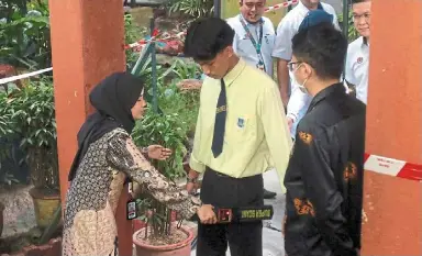  ?? ?? Taking precaution­s: a SMK Kampong Pasir Puteh student being scanned for electronic items such as smartphone­s and smartwatch­es before being allowed to enter the exam hall. — ronnie Chin/the Star
