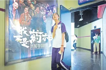  ??  ?? In this picture taken on July 12, 2018, a girl walks past a poster of the film ‘Dying to Survive' at a cinema in Beijing. The screen portrayal of a cancer sufferer whose illegal import of foreign medicines into China spurred national policy changes has...