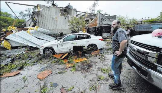  ?? Gerald Herbert The Associated Press ?? People stand outside the heavily damaged building of E.C.O. Builders in Slidell, La., on Wednesday, in the aftermath of severe storms that swept through the Southeast and began moving up into Kentucky, Ohio and West Virginia on Thursday.