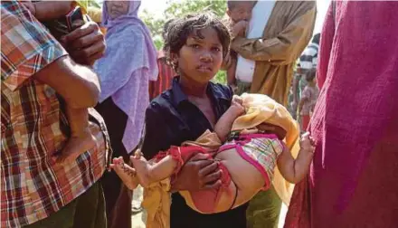  ??  ?? A Rohingya girl carrying a baby outside a food distributi­on centre at Kutupalang Unregister­ed refugee camp in Cox’s Bazar, Bangladesh.