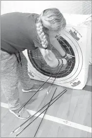  ?? SALLY CARROLL/MCDONALD COUNTY PRESS ?? Lillian Heithaus pulls her arrows out of the target at the end of practice. Students in grades five through eight meet after school at White Rock Elementary School twice a week to learn more about proper form and how to sharpen their shooting abilities...