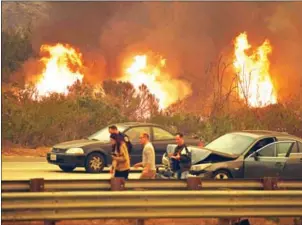  ?? MARK RALSTON/AFP ?? A woman involved in a traffic accident waits to get towed beside a wall of flames during the Thomas wildfire near Ventura, California, on Wednesday.