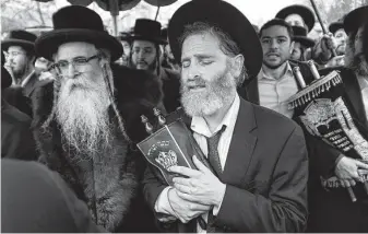  ?? Craig Ruttle / Associated Press ?? Hasidic Jews in Monsey, N.Y., including Rabbi Chaim Rottenberg, left, celebrate a new Torah’s arrival Sunday. The previous night, five people were stabbed in an attack at the rabbi’s home.