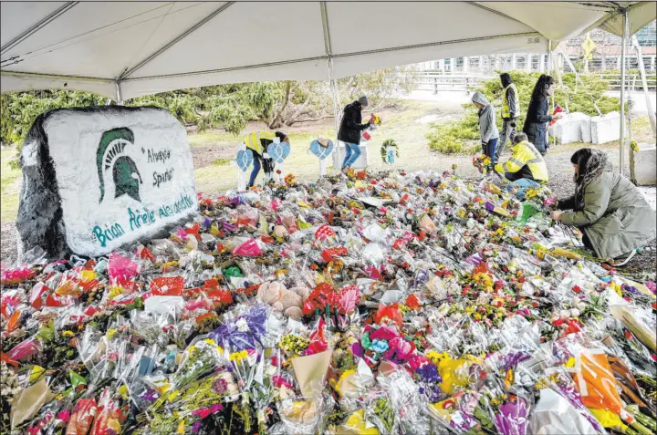  ?? Nick Kang Lansing State Journal ?? People gather at a memorial at the Rock in honor of three students killed on campus this year at Michigan State University .