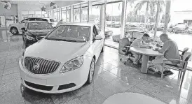  ?? [AP PHOTO] ?? Client specialist Felipe A. Perdomo, left, closes a deal with customer John Tsialas at a GMC Buick dealership in Miami. U.S. household debt reached a record high in the first three months of 2017, topping the previous peak reached in 2008. Yet the...