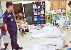  ?? RESCUE CENTRE/AFP AO LUEK ?? Local rescue workers gather over the bodies of victims of a shooting at a residence in the southern Thai province of Krabi yesterday.