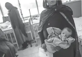  ?? BERNAT ARMANGUE/AP ?? An Afghan woman holds her 5-month-old daughter, Samina, at the malnutriti­on ward of the Indira Gandhi Children Hospital in Kabul, Afghanista­n, on Wednesday. The question of how the world will get aid to Afghan citizens without enriching Taliban rulers is haunting the country.