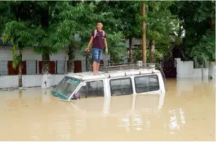  ?? AFP ?? A resident stands on the roof of a partially submerged car after a heavy downpour at Kailasahar, some 156 kms north of Agartala, the capital of northeaste­rn state of tripura. —