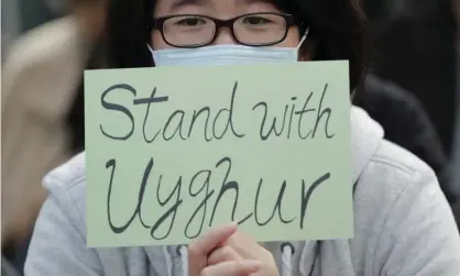  ??  ?? A man holds a sign at a Hong Kong rally to support Uighurs. The former national security adviser John Bolton, in his new book, claims that Mr Trump actively encouraged Xi Jinping to continue the mass incarcerat­ion of Uighurs. Photograph: Lee Jin-man/AP